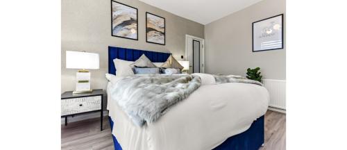 een slaapkamer met een groot wit bed met een blauw hoofdeinde bij Serene, Stylish, Spacious Brand New for 2023! in Londen