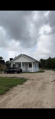 une voiture noire garée devant une maison blanche dans l'établissement Bonjour mini house & campsite, à Bachok