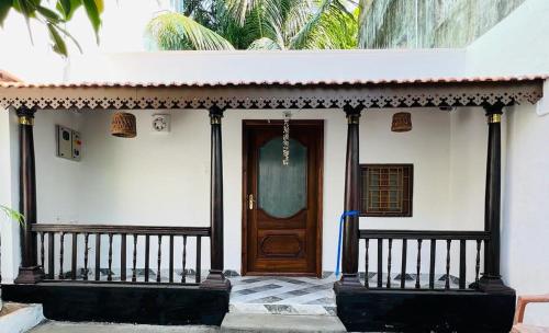 dom z drewnianymi drzwiami i werandą w obiekcie Villa De Jeff w mieście Puducherry