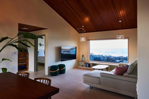 a living room with a couch and a large window at Hey Day Jeju in Jeju