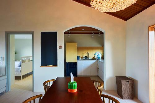 a dining room with a table and a kitchen at Hey Day Jeju in Jeju