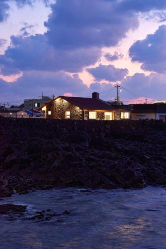 a house on the shore of a body of water at Hey Day Jeju in Jeju