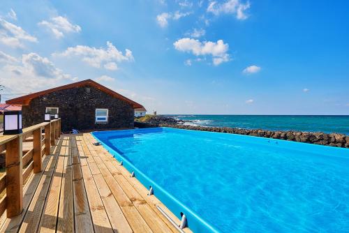 a swimming pool on a deck next to the ocean at Hey Day Jeju in Jeju