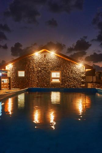 a stone house with a swimming pool at night at Hey Day Jeju in Jeju