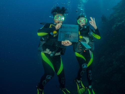 two people are standing in the water with a sign at Liberty's Lodge and Diving - Apo Island in Dumaguete
