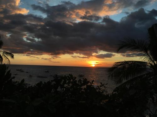 a sunset over the ocean with boats in the water at Liberty's Lodge and Diving - Apo Island in Dumaguete