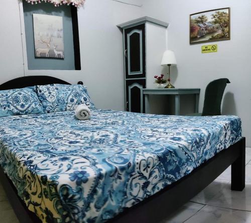 a bedroom with a bed with a blue and white comforter at Center Parkway Pension House in Kalibo