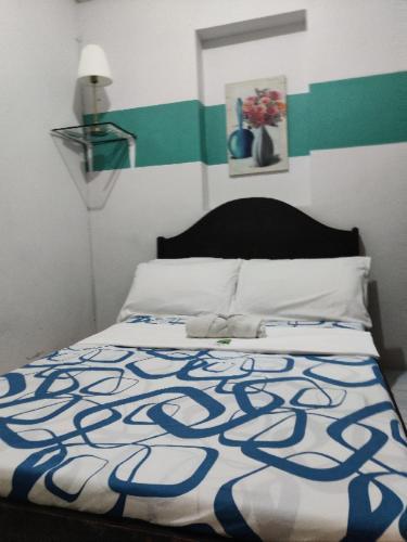 a bedroom with a bed with a blue and white blanket at Center Parkway Pension House in Kalibo