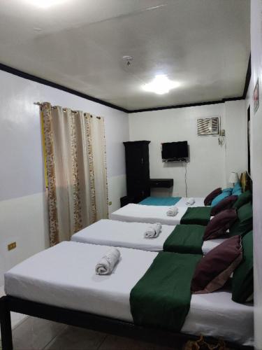 a group of three beds in a room at Center Parkway Pension House in Kalibo
