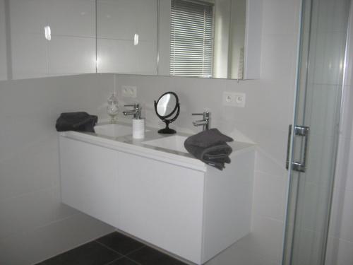 a white bathroom with a sink and a mirror at Nobel in Middelkerke