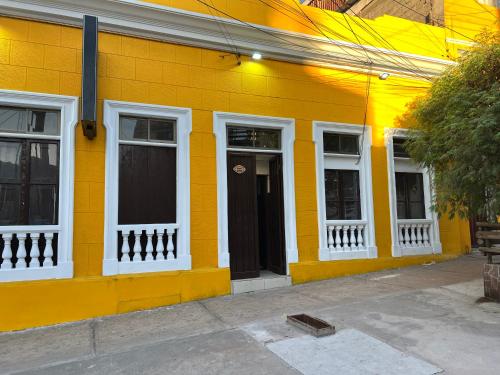 un edificio amarillo con ventanas blancas y una puerta en Hostal La Mansion, en Antofagasta