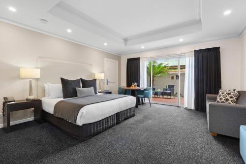 All Seasons Resort Hotel Bendigo في بنديجو: غرفة نوم بسرير ومكتب واريكة