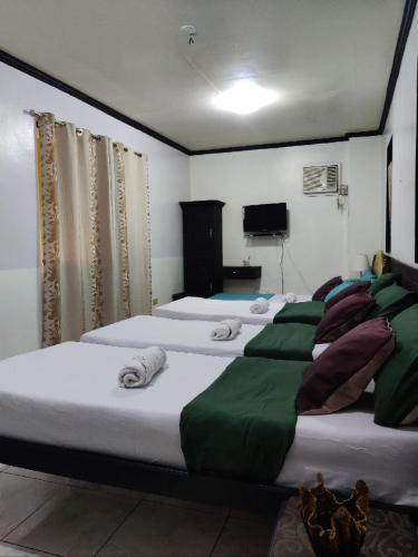 a bedroom with three beds with towels on them at Center Parkway Pension House in Kalibo