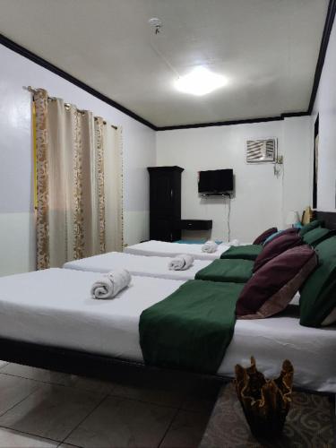 a bedroom with three beds with towels on them at Center Parkway Pension House in Kalibo