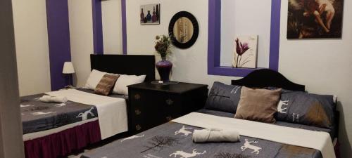 two beds in a room with purple walls at Center Parkway Pension House in Kalibo