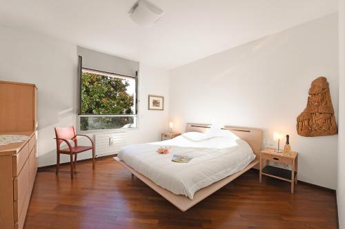 een witte slaapkamer met een bed en een raam bij Sweet Lake View Lugano - Happy Rentals in Lugano