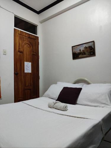 a bedroom with a white bed with a wooden door at Center Parkway Pension House in Kalibo