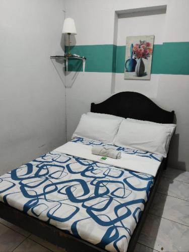 a bedroom with a bed with a blue and white blanket at Center Parkway Pension House in Kalibo