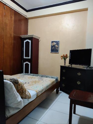 a bedroom with a bed and a desk with a computer at Center Parkway Pension House in Kalibo
