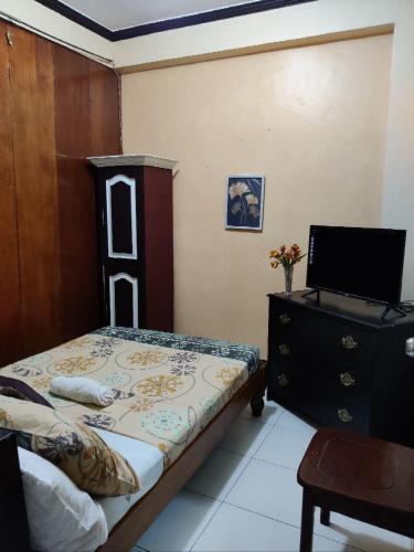 a bedroom with a bed and a dresser with a television at Center Parkway Pension House in Kalibo