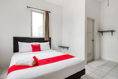 1 dormitorio con 1 cama blanca grande con almohadas rojas en RedDoorz Plus near Galaxy Mall, en Watulawang