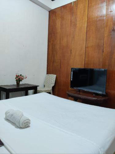 a bedroom with a bed and a tv and a table at Center Parkway Pension House in Kalibo