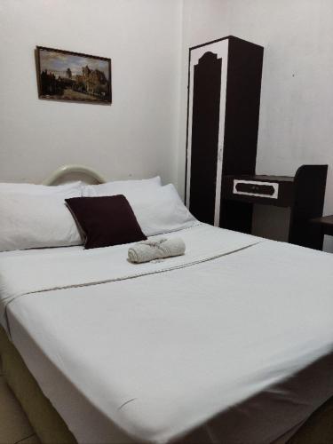 a large white bed in a room with a desk at Center Parkway Pension House in Kalibo