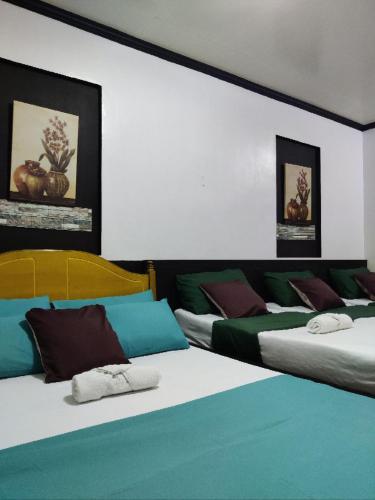 two beds in a room with green and white at Center Parkway Pension House in Kalibo