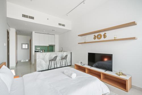 a white bedroom with a bed and a tv at Hidden Gem Studio - Affordable in Dubai