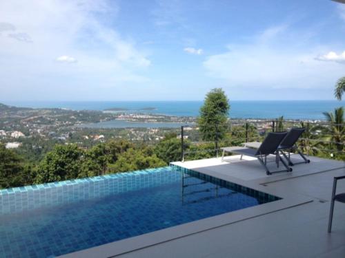 a swimming pool with two chairs and a view of the ocean at Great Sea View Mountain Villa Koh samui in Nathon Bay