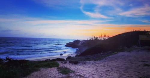 a sunset on a beach with the ocean at Hakha Beach House in Praia do Tofo