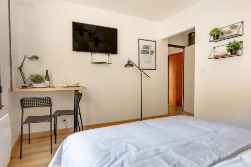 une chambre avec un lit, un bureau et une télévision dans l'établissement Suites indépendantes toutes équipées Leopold ou Carnot, à Nancy