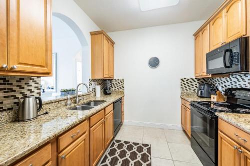 a kitchen with wooden cabinets and a sink at Top Floor*Balcony*VistaCay Convention Ctr & Idrive in Orlando