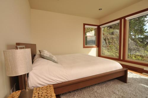 a bedroom with a bed and two windows at Exclusive Private Island - Pacific Ocean Paradise in Madeira Park