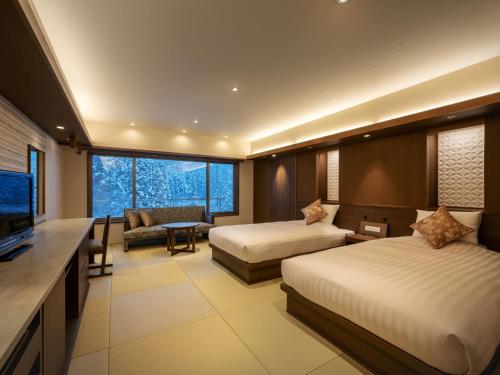 a hotel room with two beds and a television at Zao Shiki no Hotel in Zaō Onsen