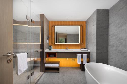 a bathroom with a tub and a sink and a mirror at Home2 Suite by Hilton Wenzhou Wencheng in Wenzhou