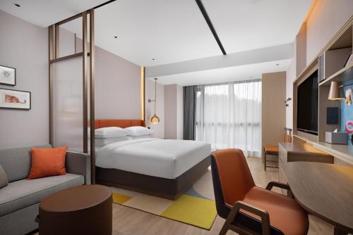 a hotel room with a bed and a living room at Home2 Suite by Hilton Wenzhou Wencheng in Wenzhou