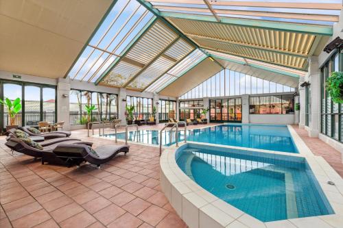 a pool in a building with a large glass ceiling at All Seasons Resort Hotel Bendigo in Bendigo