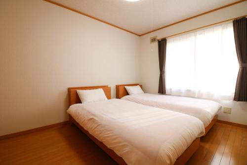 2 camas en una habitación con ventana en Relax House Misato, en Shiraoi