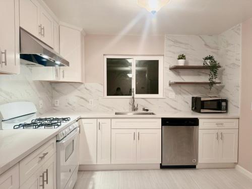 eine weiße Küche mit einer Spüle und einer Mikrowelle in der Unterkunft New remol modern tranquil house near SFO in San Mateo