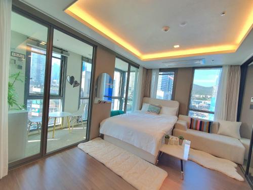 a bedroom with a bed and a couch and windows at Haeundae Ocean Family in Busan