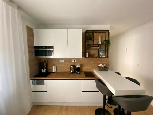 cocina con armarios blancos, mesa y sillas en PannaRoza Apartman en Balatonlelle