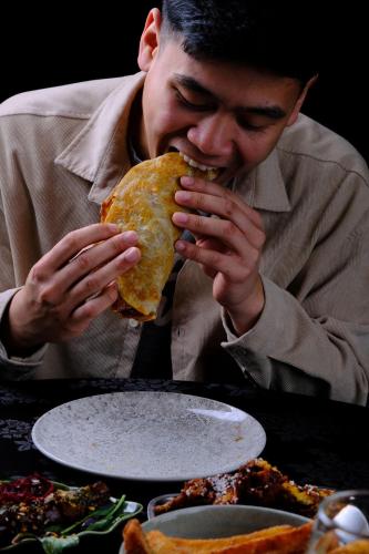 a man eating a sandwich in front of a table at Law Courts Hotel in Dunedin