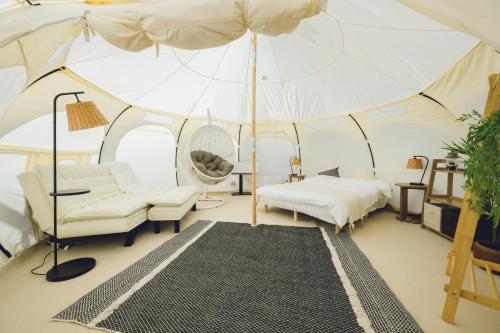 Zimmer mit einem Zelt mit einem Bett und einem Sonnenschirm in der Unterkunft Yagaji Beach(屋我地ビーチ) in Nago