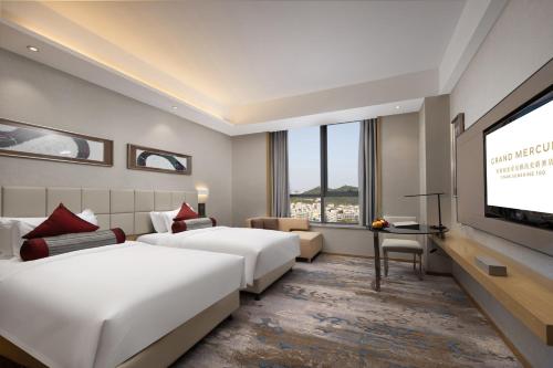 um quarto de hotel com duas camas e uma televisão de ecrã plano em Grand Mercure Jinan Sunshine em Jinan
