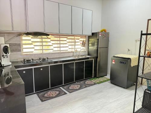 una cucina con armadietti bianchi e neri e un frigorifero di OH MY BATU RAKIT HOMESTAY Terengganu a Kuala Terengganu