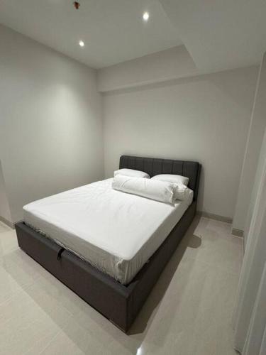 a bed with white sheets and pillows in a room at West Vista Studio Apartment with Netflix in Jakarta