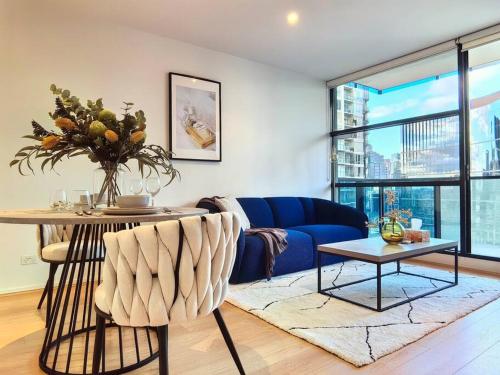 a living room with a blue couch and a table at Charming 1BR Southbank w balcony & free parking#TI22 in Melbourne