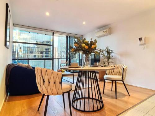 a living room with a table and chairs and a couch at Charming 1BR Southbank w balcony & free parking#TI22 in Melbourne