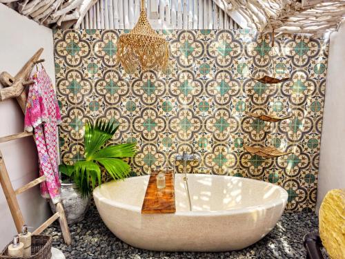 a bathroom with a bath tub and a wall at Janur Bungalow in Borobudur